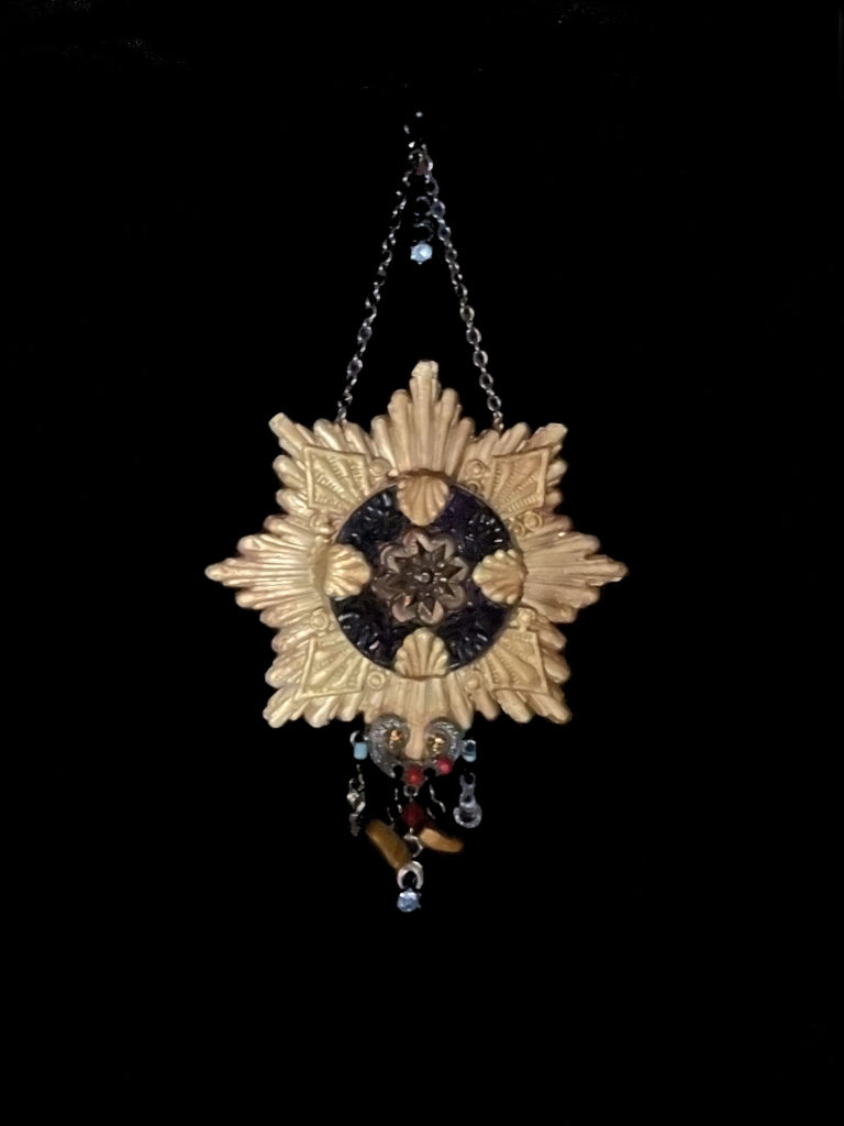 A bold black and gold pendant with colorful dangling accents.