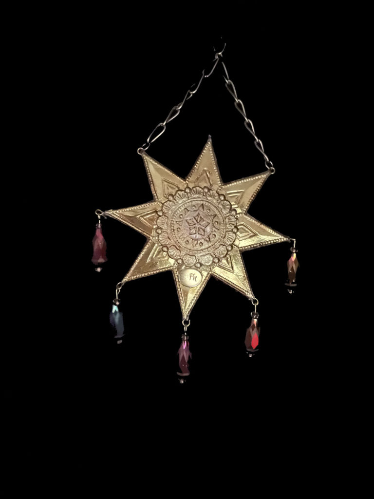 Right at home amidst the elaborate costumes of carnival in Venice is this pendant. An octagram in shape, iridescent glass drops dangle from the star points and a topaz colored crystal with a dragon carving is at the center.