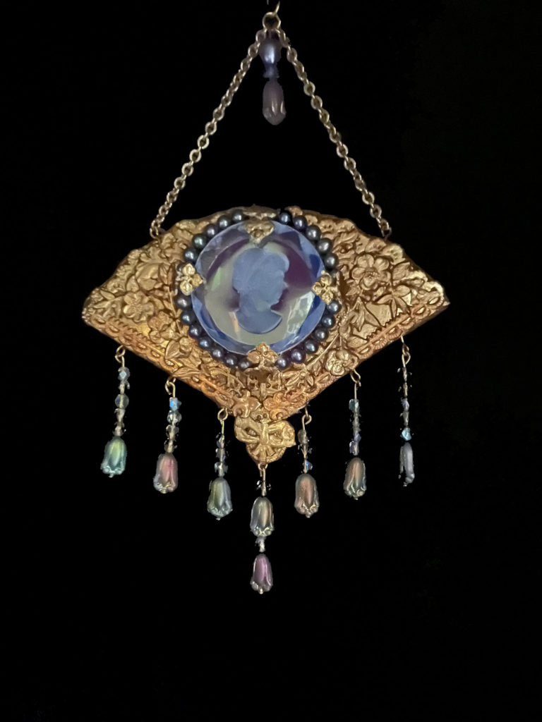 M’lady’s fan is enhanced with a blue intaglio cameo framed by pearls. Iridescent tulip-shaped beads fringe the pendant.