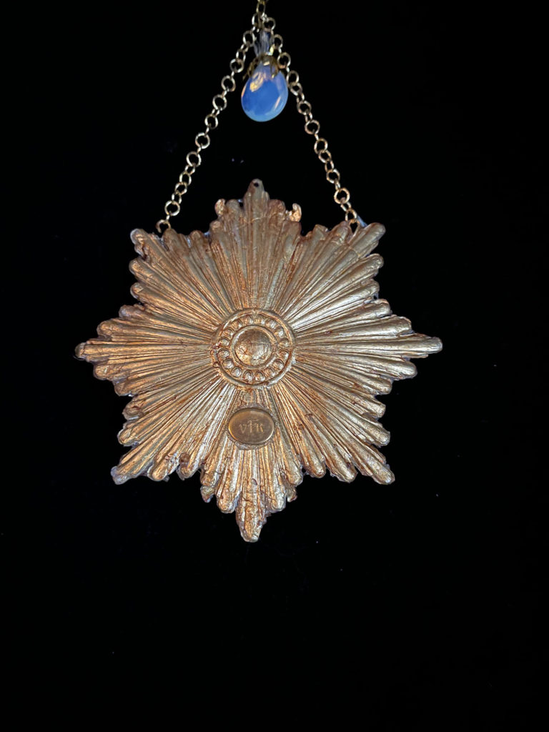 A graceful Swan floats on a golden sunburst embellished with glowing Opalite and clear rhinestones and suspended from a cream-colored velvet choke