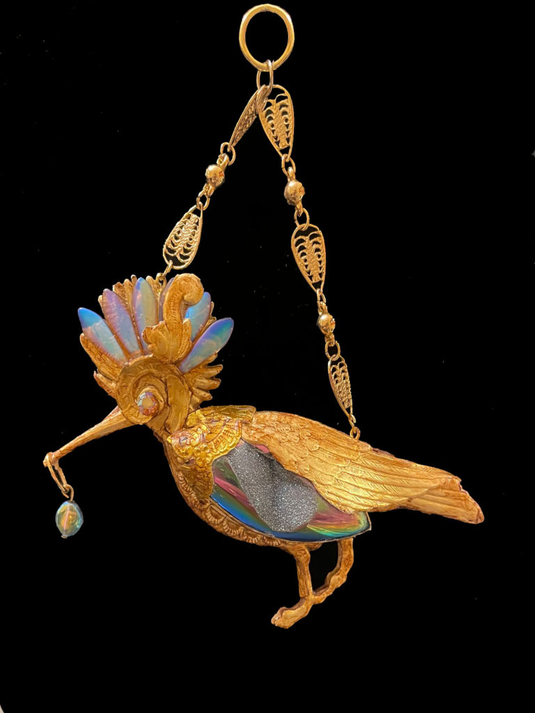 With her iridescent feather crown, Queen Hoopoe rules her domain. Her body sparkles with a titanium coated sugar crystal Druzy and a small glass bead dangles from her long beak.